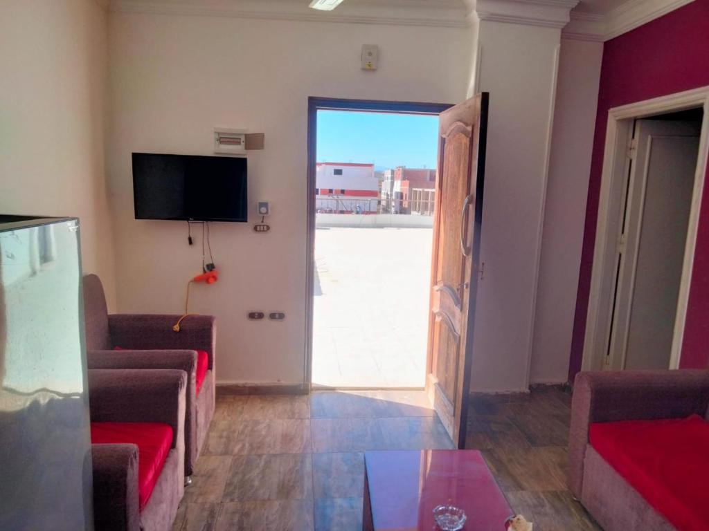a living room with a couch and a tv and a door at Guest House Alam w in Marsa Alam City