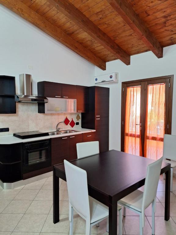 eine Küche mit einem schwarzen Tisch und weißen Stühlen in der Unterkunft Casa Ponente e Casa Levante in Buggerru