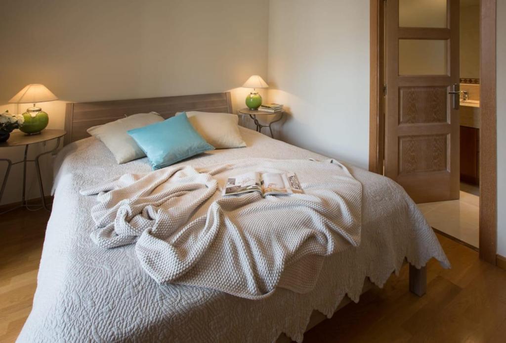 uma cama com cobertores brancos e almofadas em Elegant 3-bedroom Apartment in the Heart of BCN em Barcelona