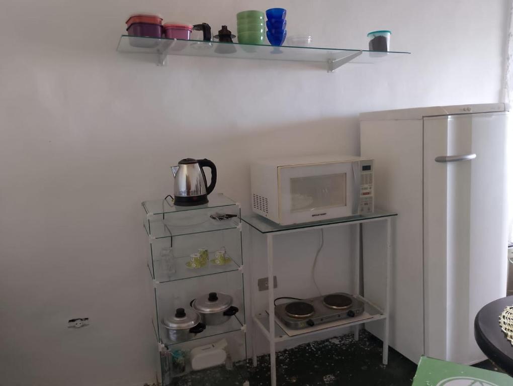 uma pequena cozinha com um micro-ondas e um frigorífico em Quarto e banheiro particular em Taboão da Serra