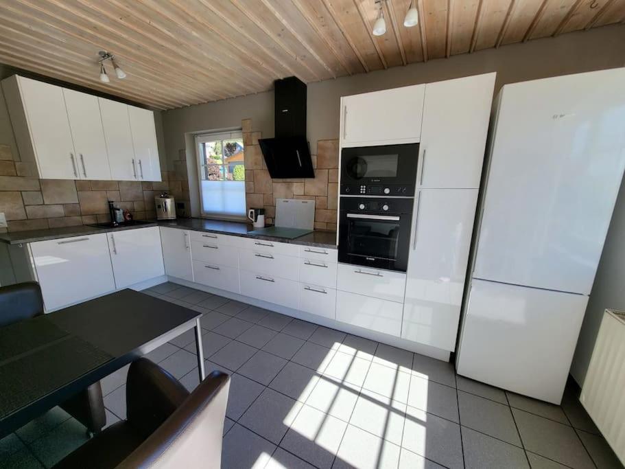 una cocina con armarios blancos y horno negro en Ferienwohnung mit ruhiger Lage, en Hilchenbach