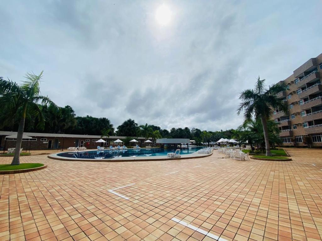 una grande piscina con ombrelloni e sedie in un cortile di Gran Lençóis Flat Residence a Barreirinhas