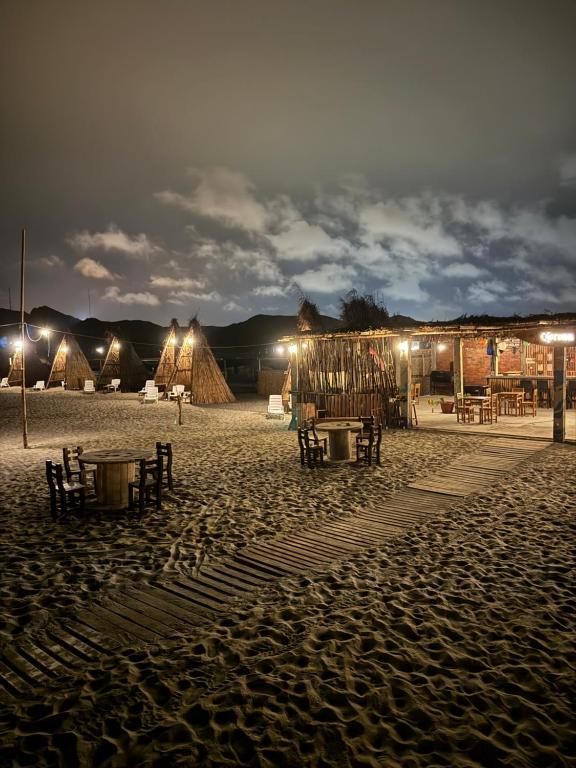 una playa de arena por la noche con mesas y tiendas de campaña en M beach, 