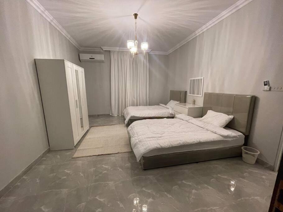 a bedroom with two beds and a chandelier at Fully furnished family house in Al Madinah