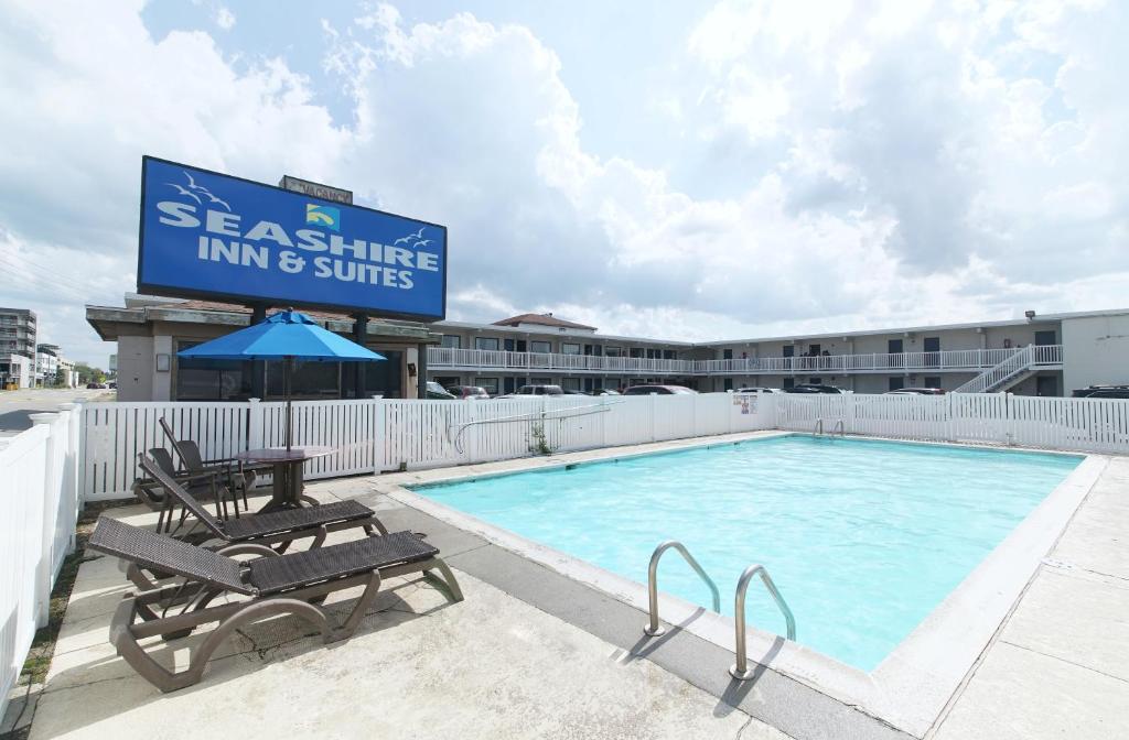 - une piscine avec un panneau indiquant une auberge et des suites dans l'établissement Seashire Inn & Suites, à Virginia Beach
