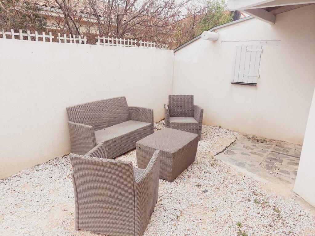 two wicker chairs and a couch on a patio at Charmante villa équipée, piscine in Le Soler