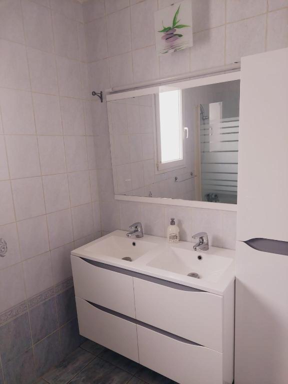 a white bathroom with a sink and a mirror at Charmante villa équipée, piscine in Le Soler