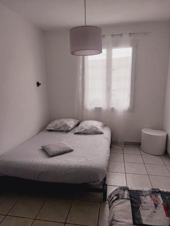 a white bedroom with a bed and a window at Charmante villa équipée, piscine in Le Soler