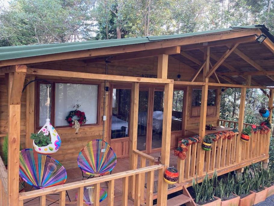 a large wooden gazebo with chairs and flowers at Cabaña en Villa de Leyva Se Permiten Mascotas Pet Friendly in Villa de Leyva