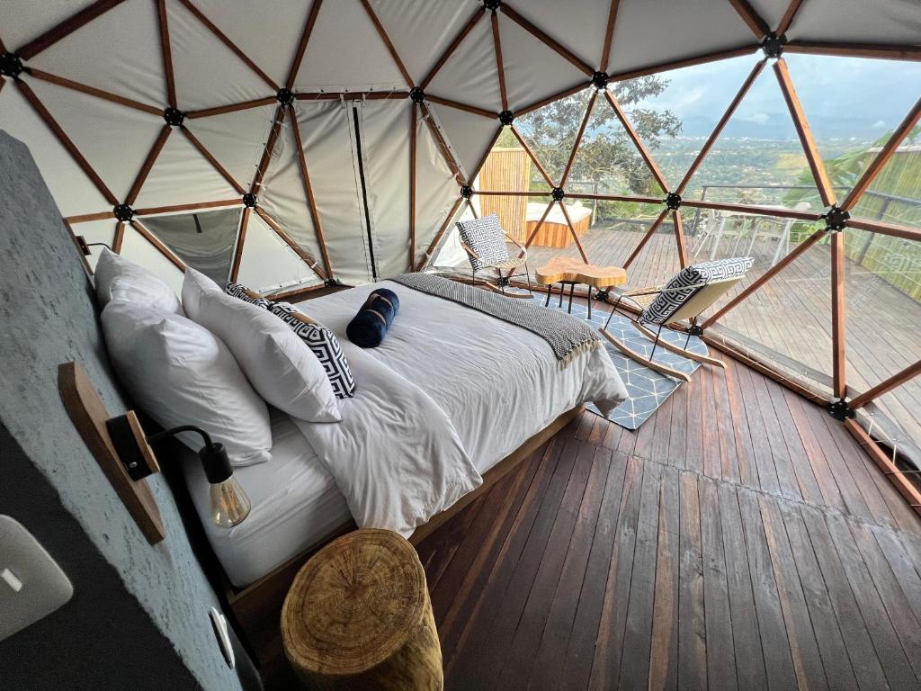 1 dormitorio en una yurta con 1 cama y sillas en URQU Glamping cerca a Bogota, en Silvania