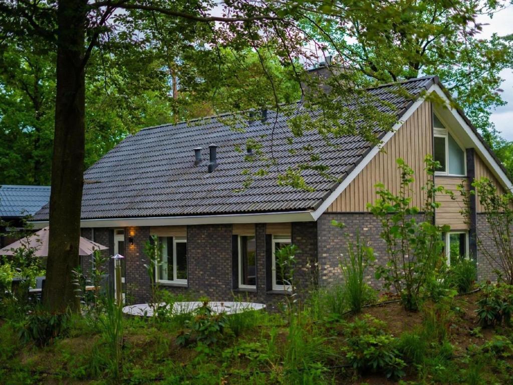 a house with a gray roof at Comfortable house with hot tub and cinema in nature in Hoenderloo