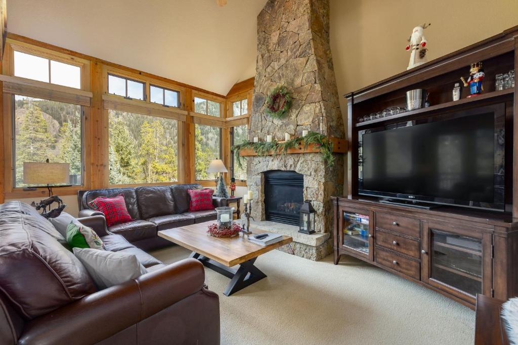 a living room with a large television and a stone fireplace at 6554 Settlers Creek townhouse in Keystone