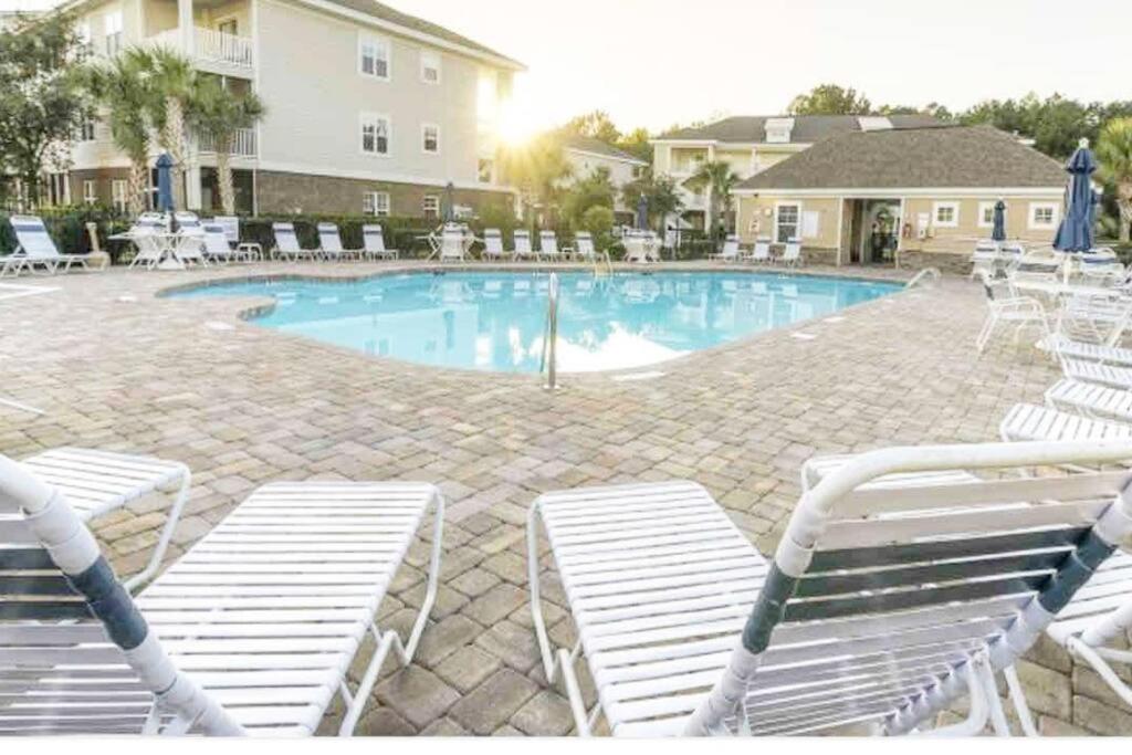 a swimming pool with white chairs in a resort at Barefoot Beach Haven: Resort Access in North Myrtle Beach