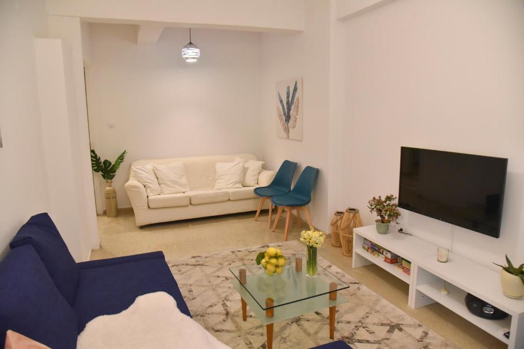 een woonkamer met een bank en een tv bij Citrus dream apartment in Athene