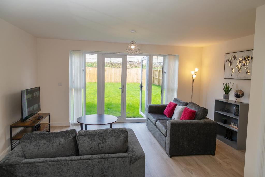 a living room with two couches and a table at Spacious New Build - Free Parking & TV in each Bedroom in Macclesfield