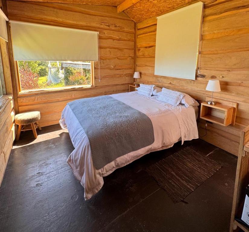 プコンにあるRefugio con Tinaja Privada 4の木造キャビン内のベッド1台が備わるベッドルーム1室を利用します。