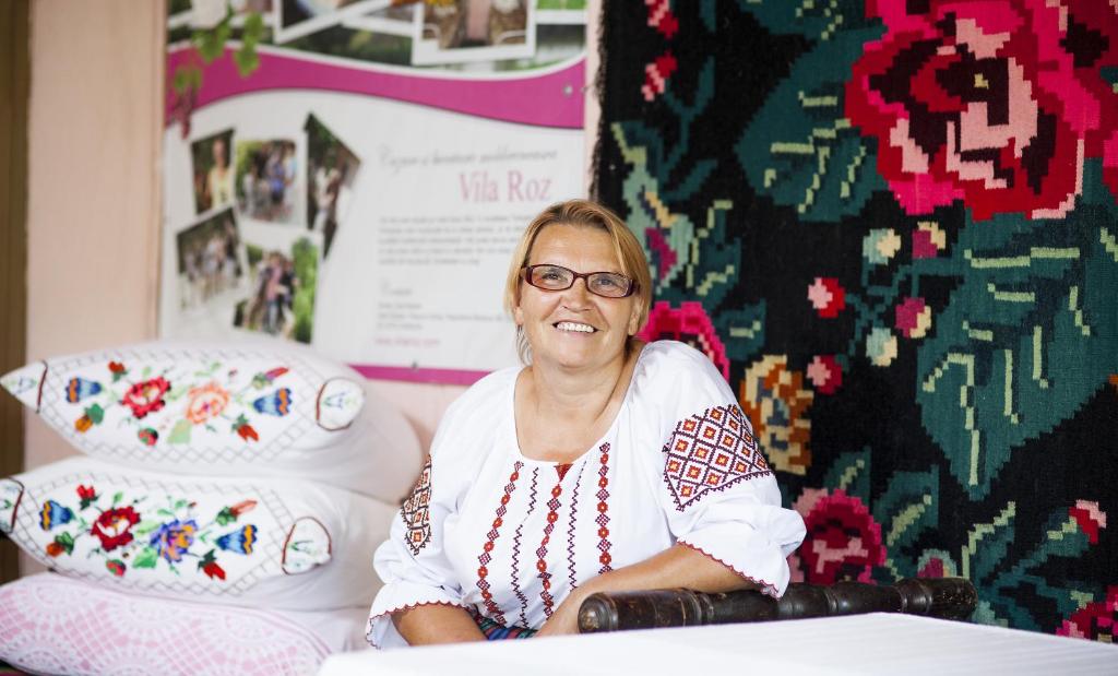 Una donna con gli occhiali seduta su un letto di Vila Roz a Trebujeni