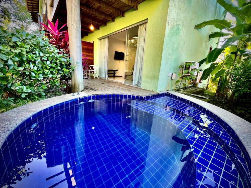 einem Pool mit blauen Fliesen vor einem Haus in der Unterkunft Bangalô Villas do pratagy com jacuzzi c in Maceió