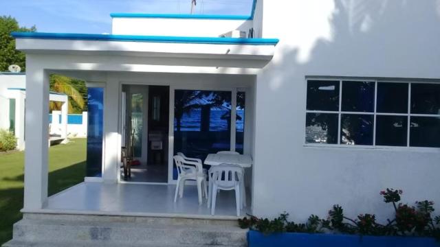 Cette maison blanche dispose d'une terrasse couverte avec des chaises et une table. dans l'établissement Sirena azul, 