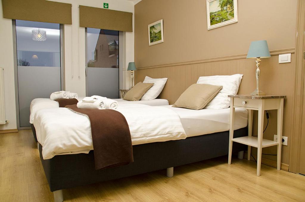 een slaapkamer met 2 bedden en een tafel met een lamp bij Hotel Apartments Belgium I in Geel