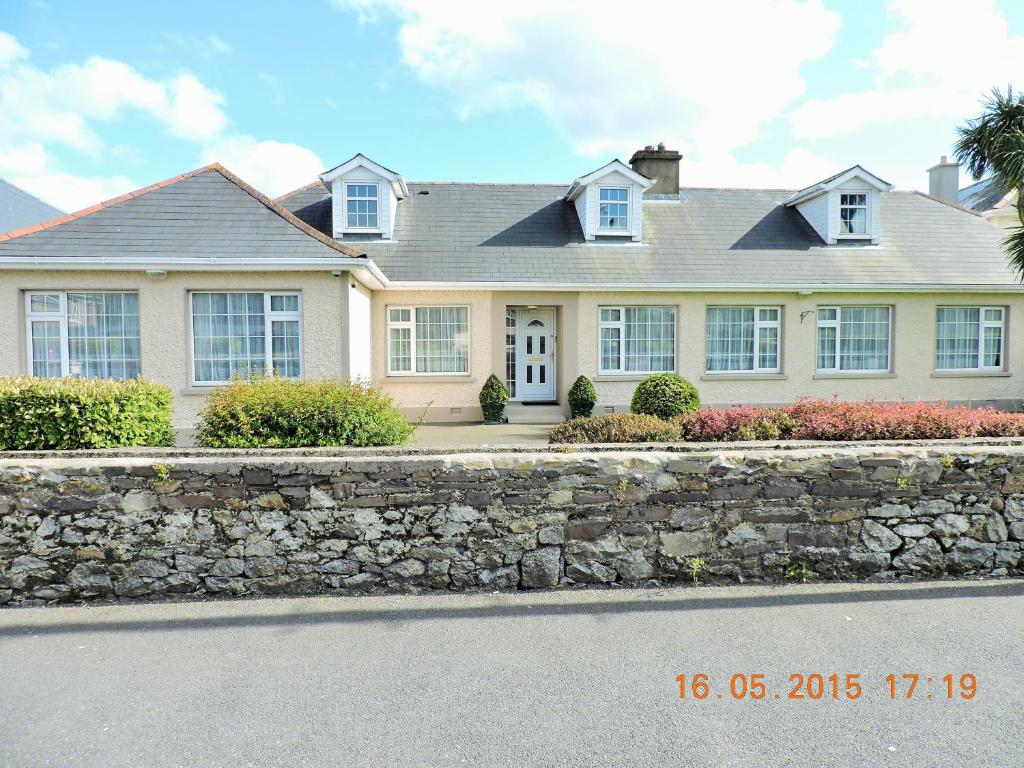 a white house with a stone retaining wall at St Anthonys B&B in Dungarvan