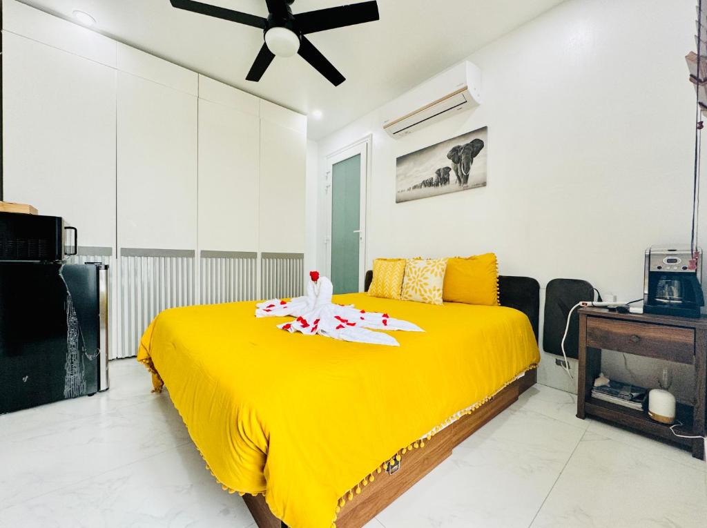 a yellow bed in a room with a ceiling fan at Ocean Pearl - A brand new one bedroom with pool, walkable distance to sunset beach in Long Bay Hills