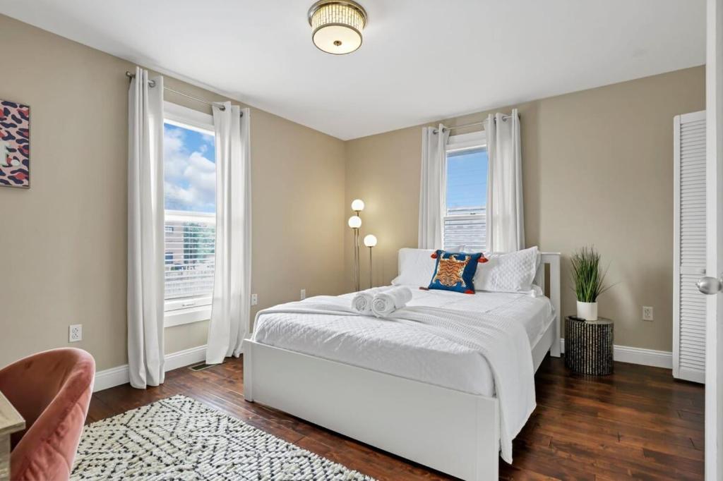 a bedroom with a white bed and two windows at Housepitality - The Columbus Game House - 2 BR in Columbus