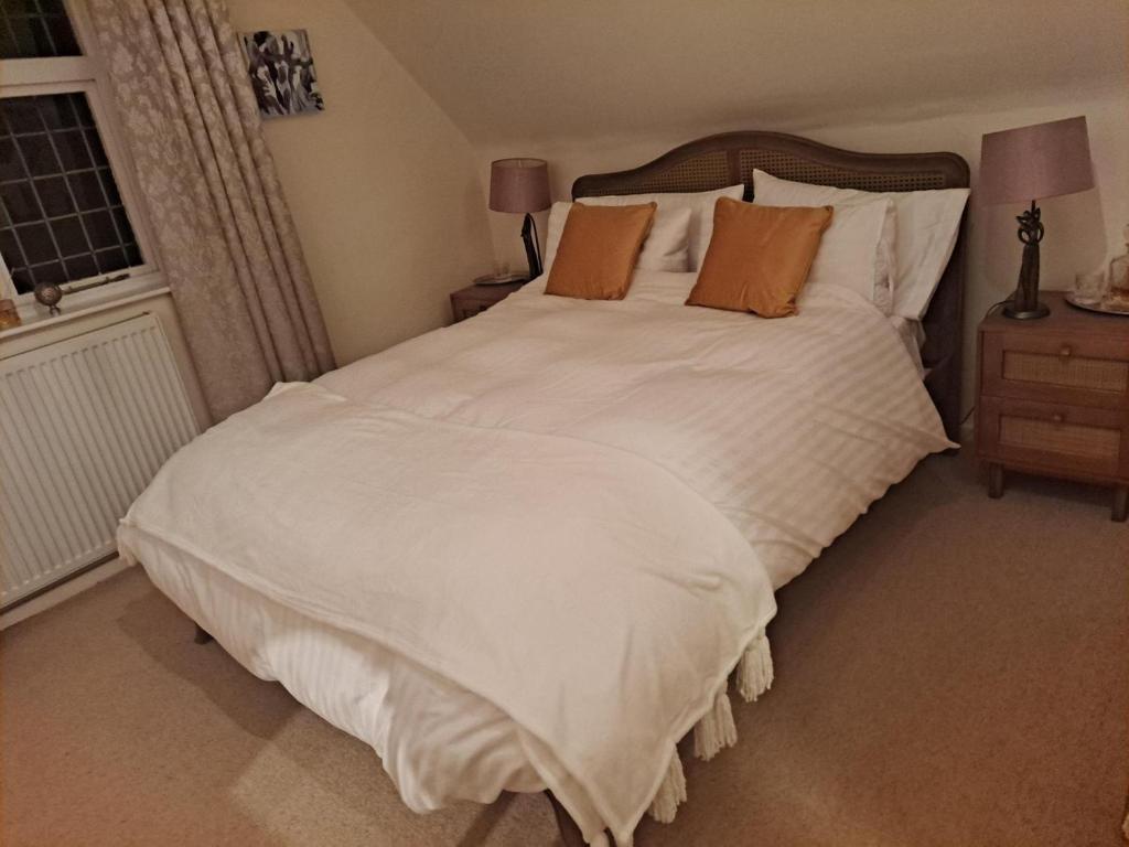 a bedroom with a large white bed with orange pillows at Lapley Manor Lodge in Gailey