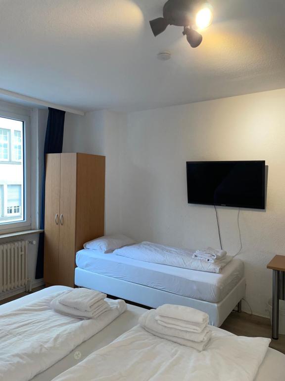 two beds in a room with a flat screen tv at TRUST Hotel & Apartment in Stuttgart
