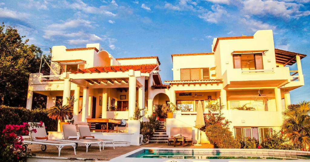 uma grande casa branca com uma piscina em frente em Villas Mykonos em Zipolite