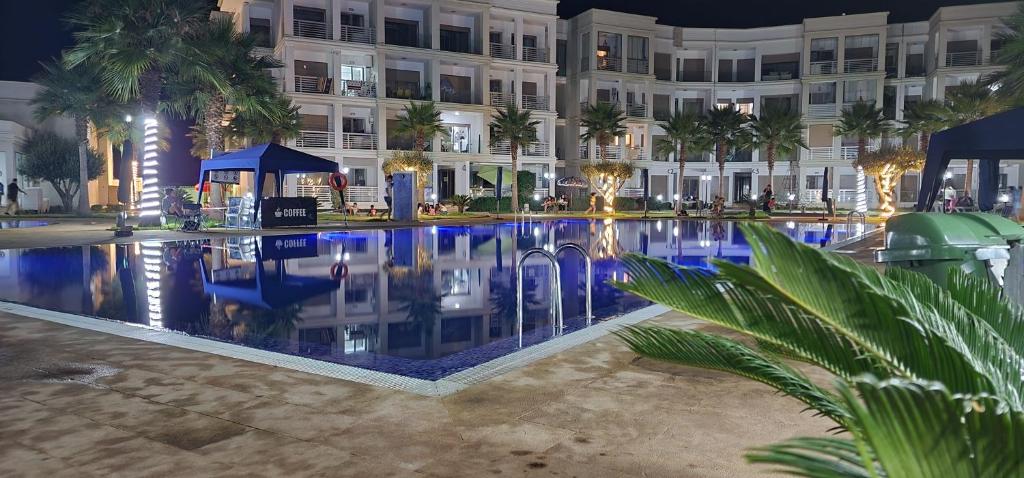 COSTA BEACH Lux Family Apartment with Pools في بوزنيقة: مسبح امام مبنى في الليل