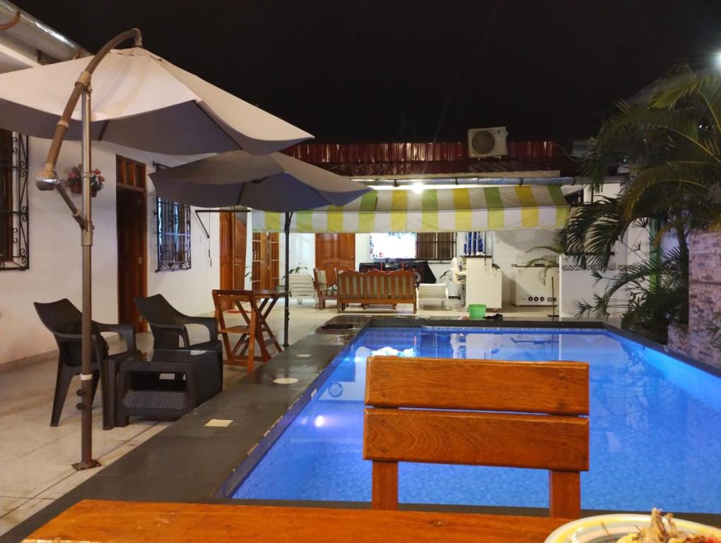 a swimming pool with a table and an umbrella at Casa Maikai Tarapoto in Tarapoto