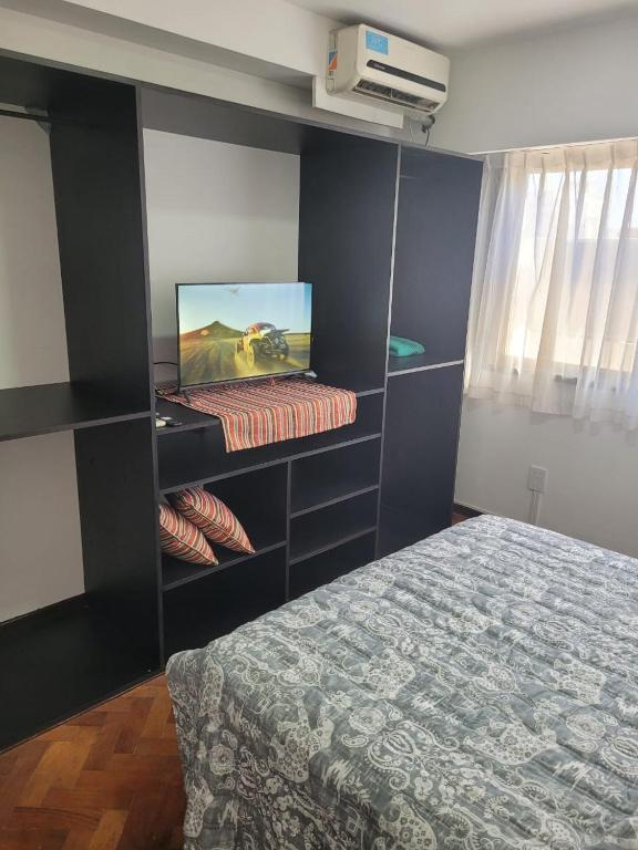 Schlafzimmer mit einem Bett und einem Schreibtisch mit einem TV in der Unterkunft Dpto España ubicadísimo!!! in Mendoza