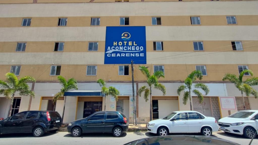 a hotel with cars parked in front of a building at Hotel Aconchego Cearense in Fortaleza