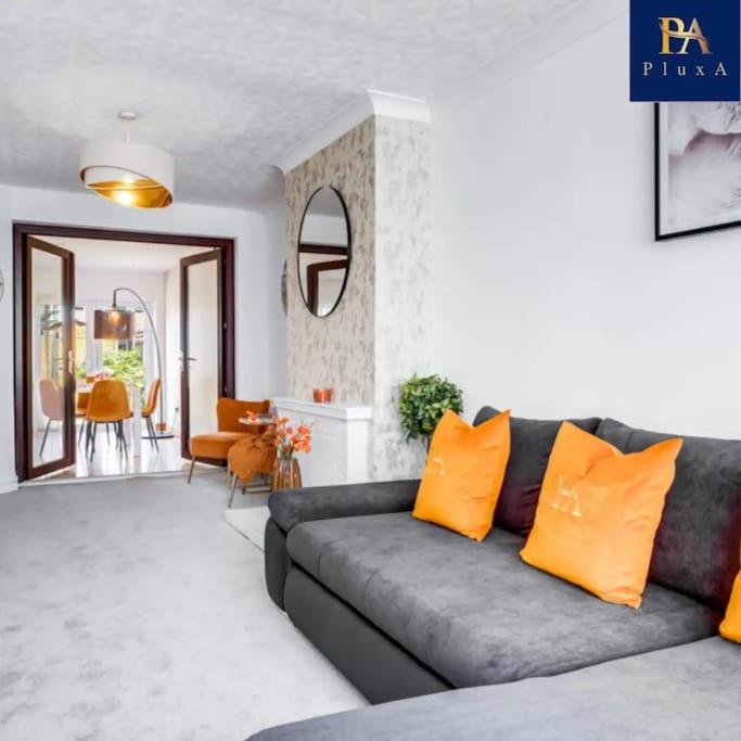 a living room with a gray couch and orange pillows at 3 Bed by Birmingham Airport in Birmingham