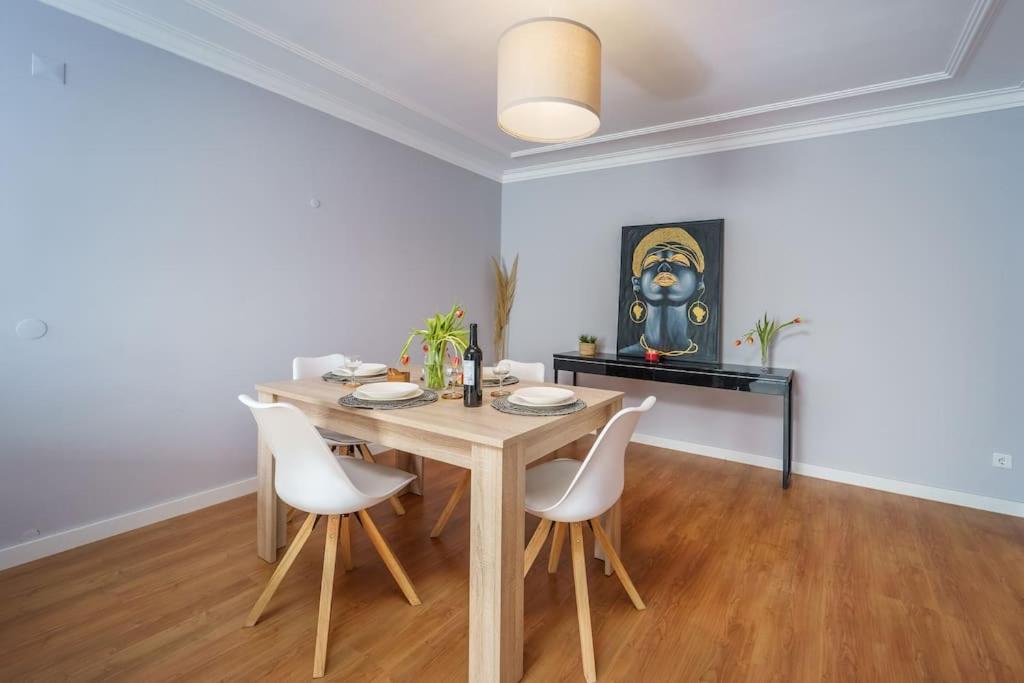 a dining room with a wooden table and white chairs at Lovely&Cozy apartment in Lagoa