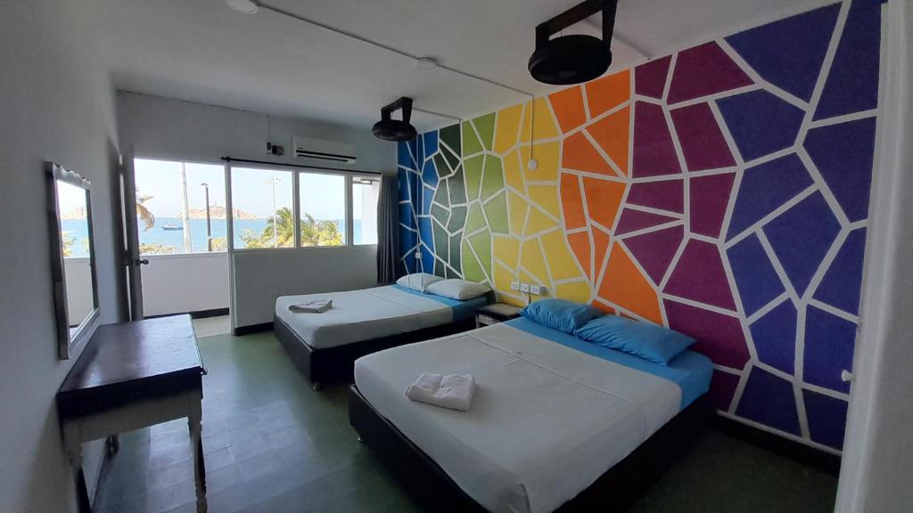 Habitación con 2 camas y pared colorida. en Panamerican Hostel, en Santa Marta