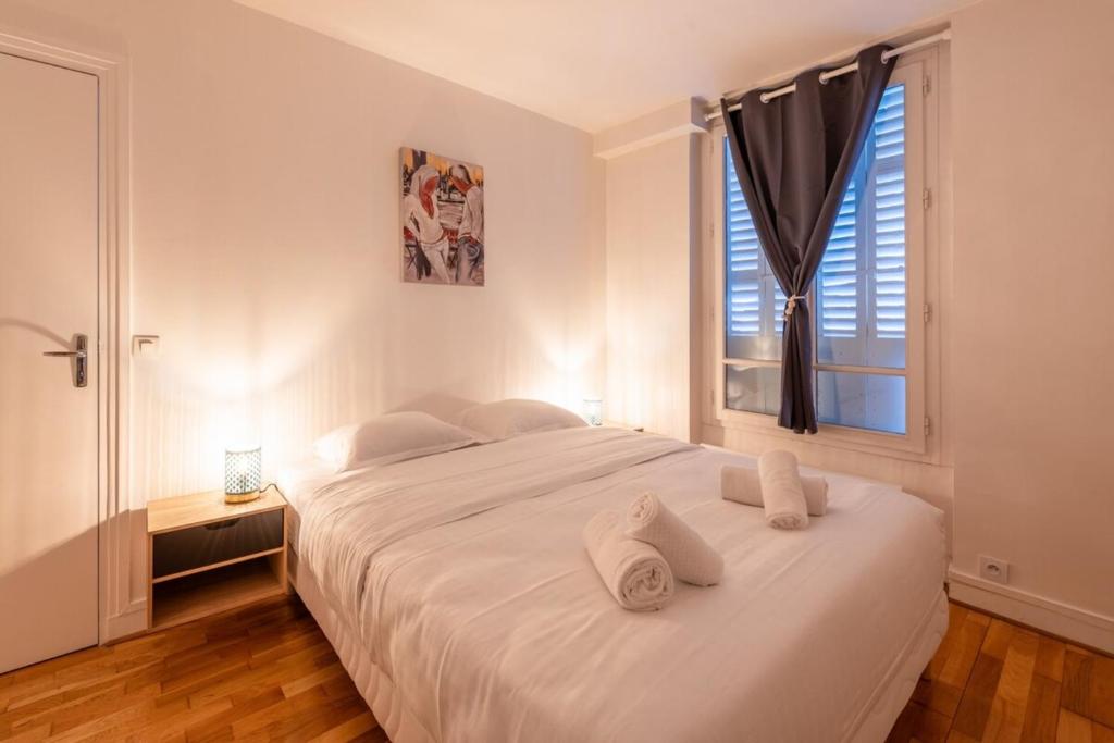 a bedroom with a bed with white sheets and a window at Cosy & Well-Connected 1BD ApartmentSaint Lazare in Paris