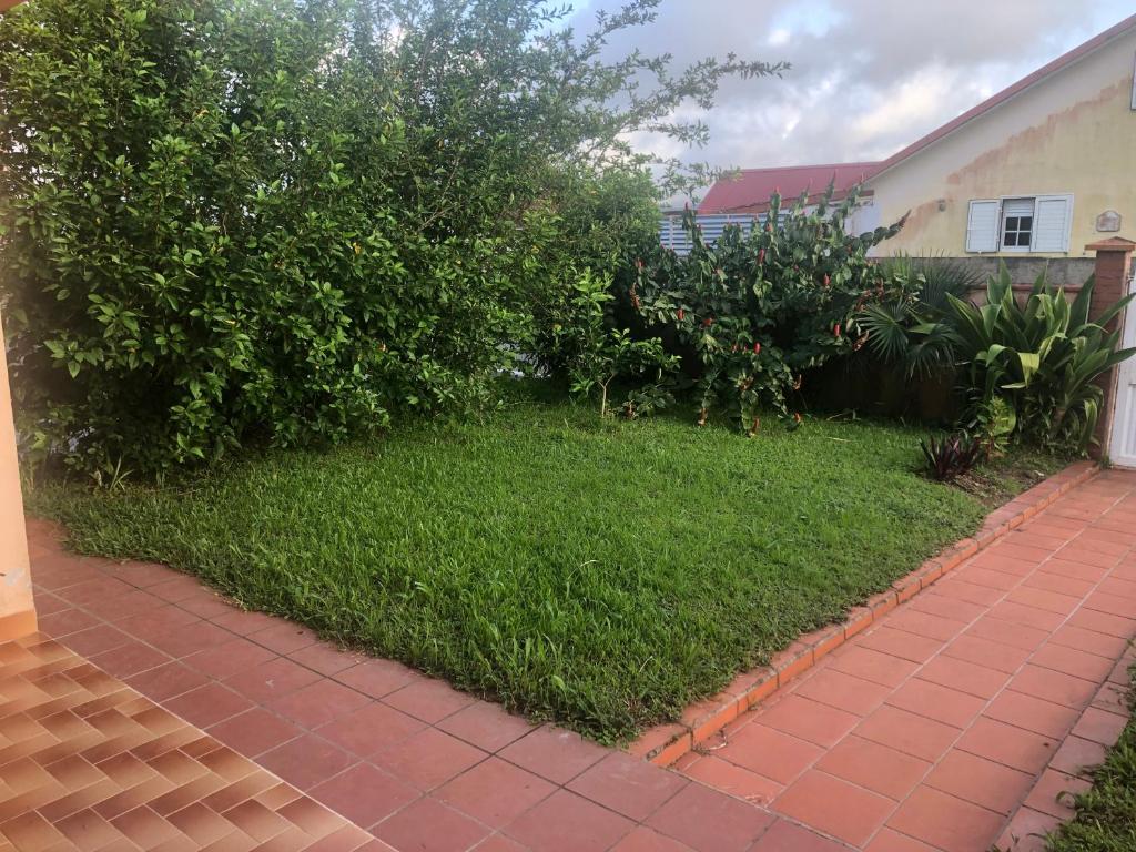 een tuin met groen gras naast een huis bij KAN'DLO in Le Morne Rouge