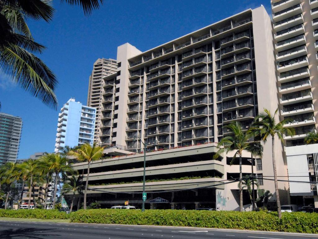 a tall building with palm trees in front of it at Aqua Palms Waikiki in Honolulu