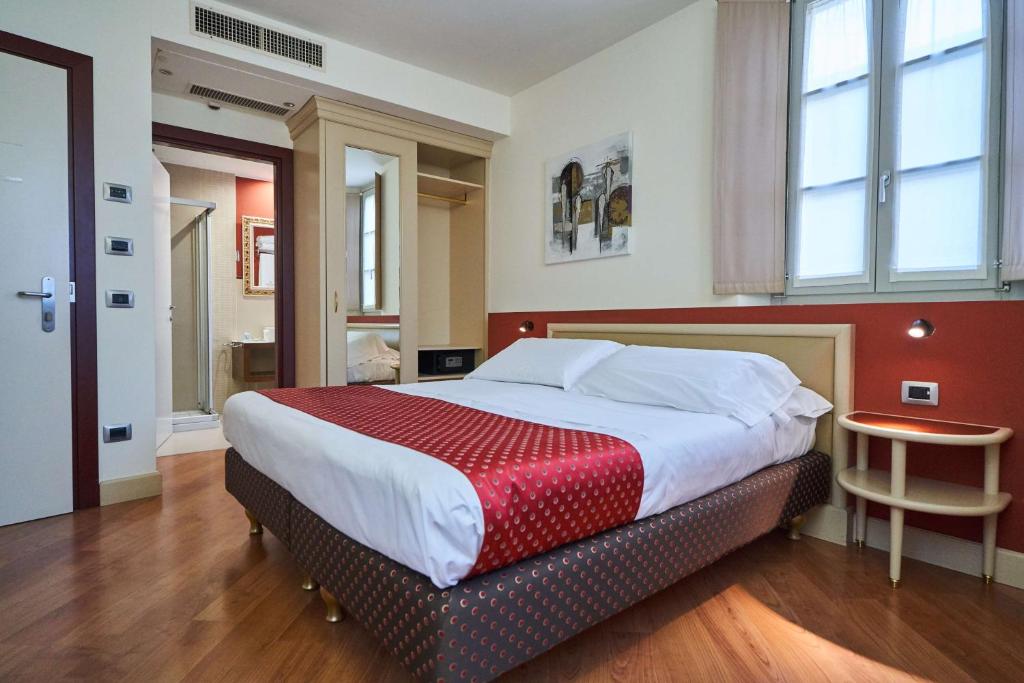 um quarto com uma cama grande e uma parede vermelha em Hotel Centrale Best Western Signature Collection em Tirano