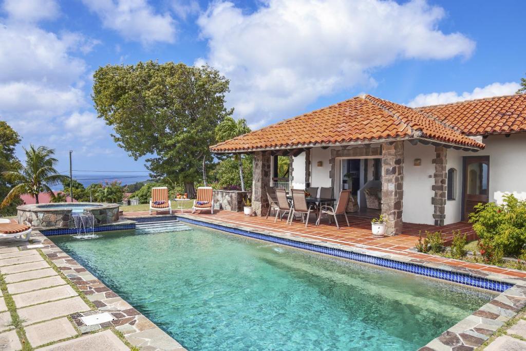 a swimming pool in front of a house at Calypso Court - Private 1 bedroom villa with pool villa in Cap Estate