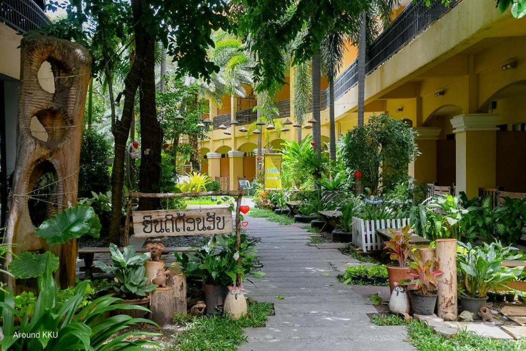 a garden in front of a yellow building with plants at Piman Garden Boutique Hotel in Khon Kaen