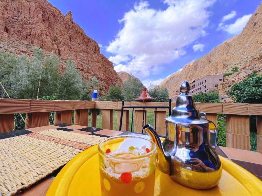 un tavolo giallo con bollitore per tè e una bevanda di Riad pizzeria Marhaba ad Akhendachou nʼAït Ouffi