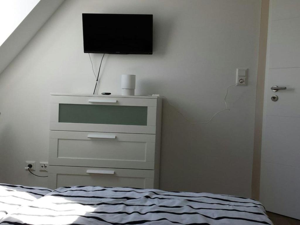 Apartment bare with ebike rental في أولدنبورغ: غرفة نوم مع خزانة وتلفزيون على الحائط
