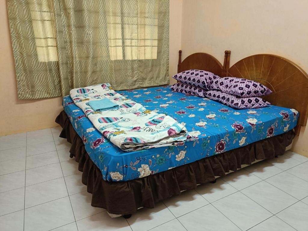 a bed with a blue comforter and pillows on it at Mahsuri Homestay in Jitra