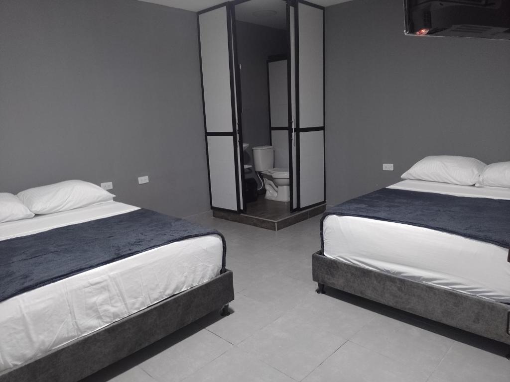 a bedroom with two beds and a mirror at Hotel Olympo in Ibagué