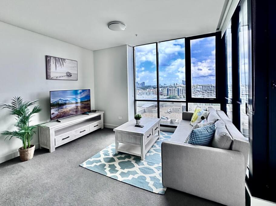 a living room with a couch and a flat screen tv at Aircabin - Wentworth Point - Sydney - 1 Bed Apt in Sydney