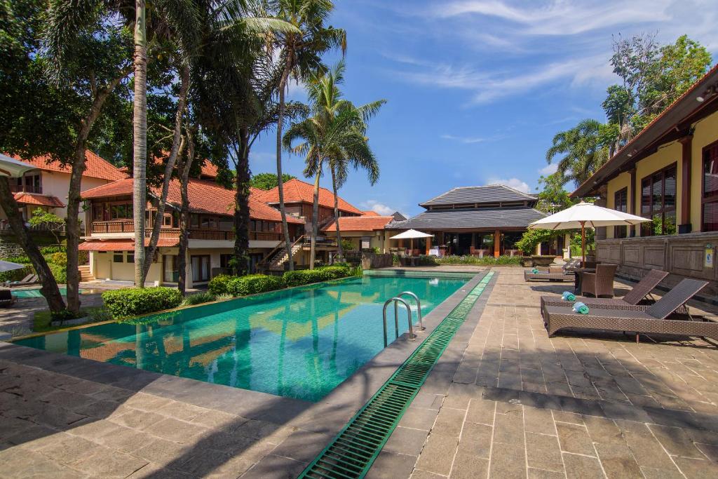 una piscina en un complejo con palmeras en Champlung Sari Hotel and Spa Ubud, en Ubud