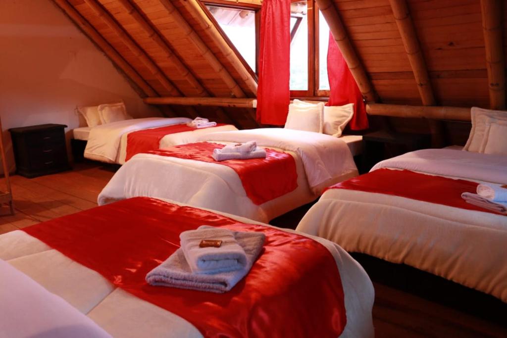 a room with four beds with red and white sheets at Hostal y Restaurante Lujans in San Agustín